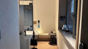 A compact hotel bathroom with a mirror, sink, and a small round table. - Youjian Hotel (Harbin Acheng Impression City) (Harbin)