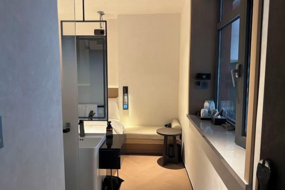 A compact hotel bathroom with a mirror, sink, and a small round table.