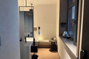 A compact hotel bathroom with a mirror, sink, and a small round table.