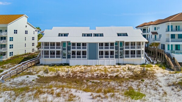 Une propriété située en bord de mer, avec un grand bâtiment principal doté de nombreux balcons et d’une entrée avant abritée.