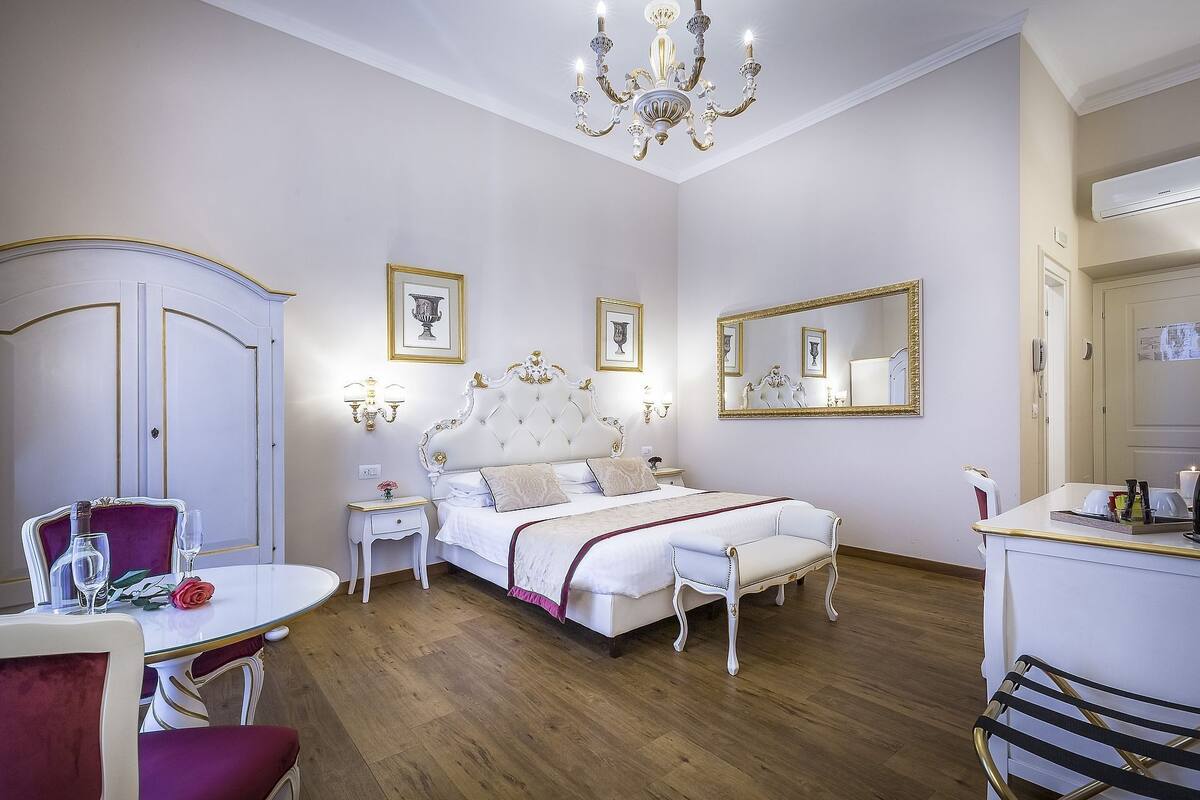 A bedroom with a bed, a vanity, a chandelier, and a mirror.