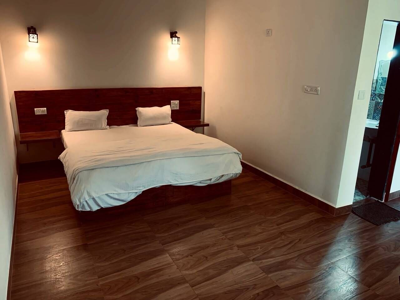 Une chambre à coucher avec une tête de lit en bois, un lit avec une literie blanche et deux appliques murales.