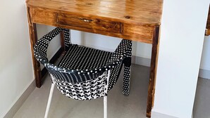 A wooden desk with a mirror, a chair with a black and white pattern, and a white wall. - Mamata Courtyard Anjuna (Anjuna)
