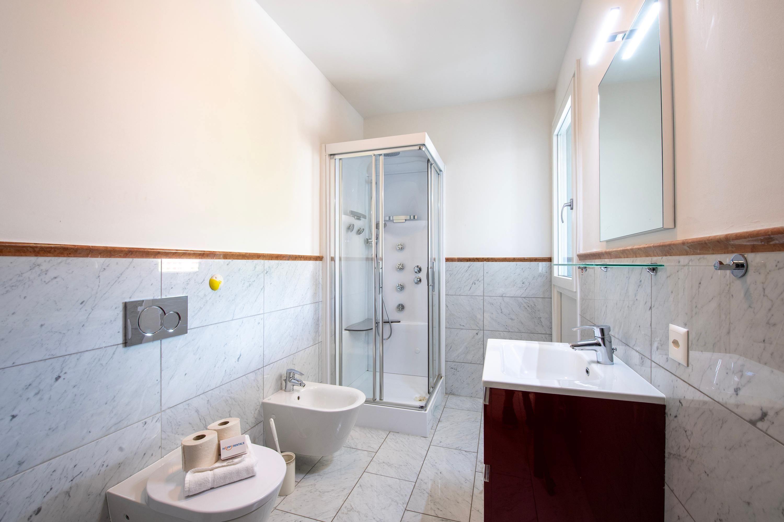 A modern bathroom with a glass-enclosed shower, a freestanding bathtub, a sink, and a toilet.