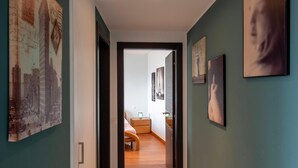 A hallway with a bed, nightstands, and artwork on the walls. - Panoramic Penthouse in Lugano (Lugano)