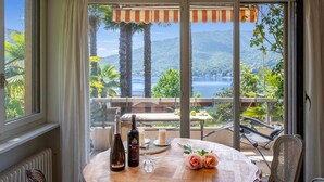 Ein Balkon mit Tisch für Zwei, mit Blick auf eine malerische Seen- und Berglandschaft.