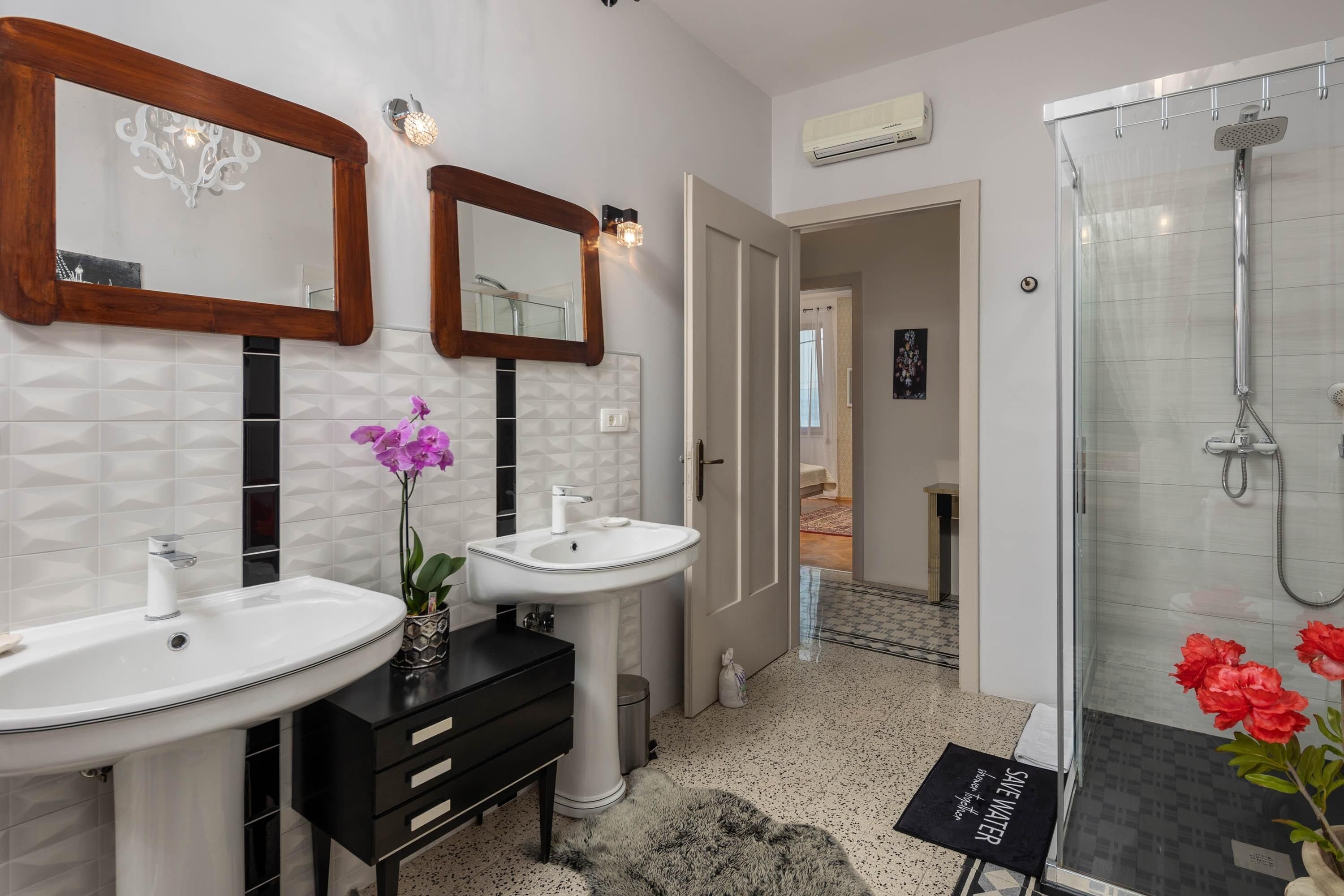 Une salle de bain moderne avec deux lavabos, un miroir et une douche.