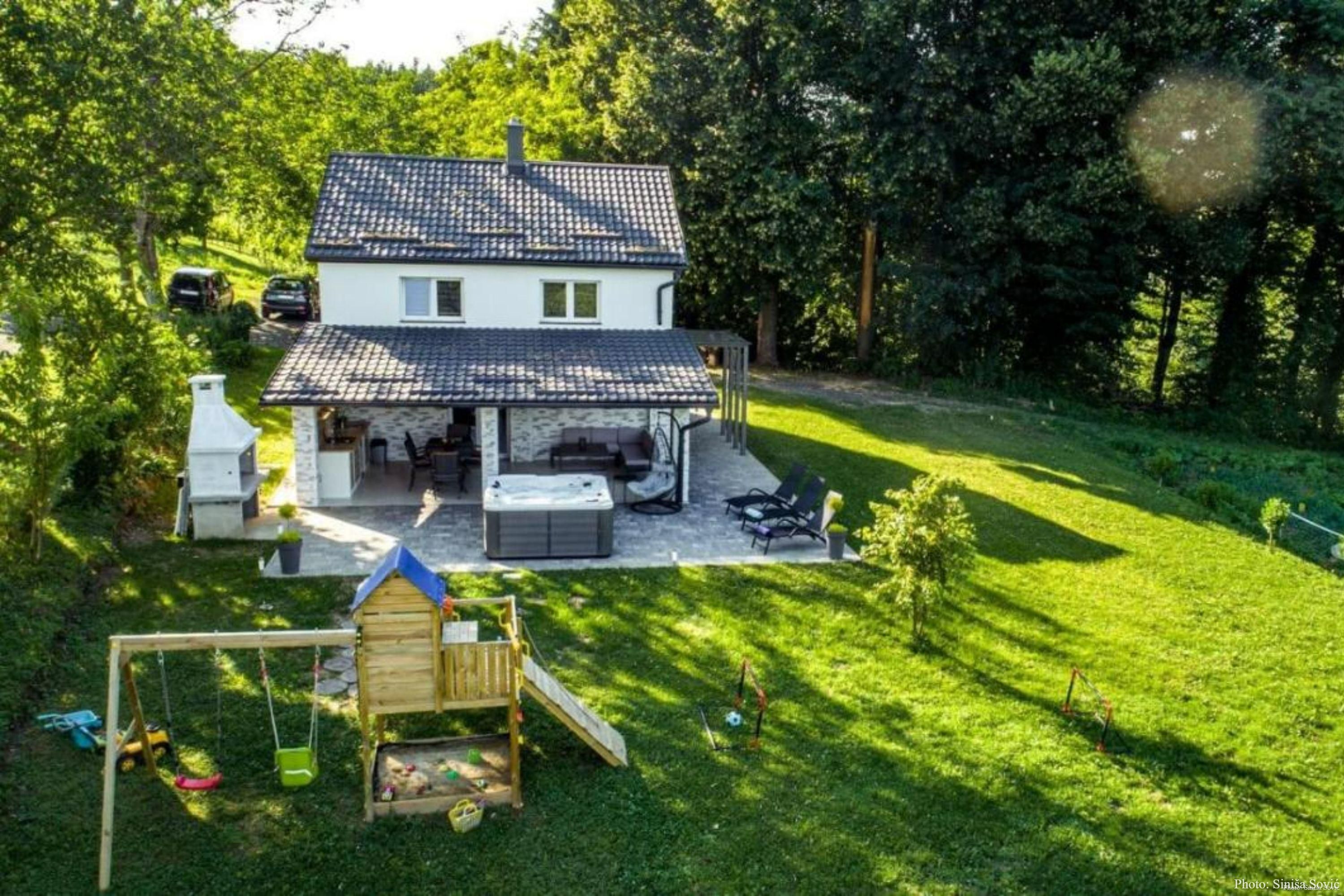 Una casa con patio, zona de juegos y jardín.