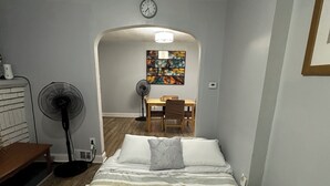 A bedroom with a bed, a wooden table, a chair, a fan, and a clock on the wall. - Cozy house in welcoming Cleveland with AC, WiFi (Cleveland)