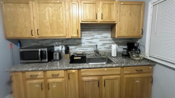 A compact kitchen with wooden cabinets, a microwave, toaster, sink, and a coffee maker. - Cozy house in welcoming Cleveland with AC, WiFi (Cleveland)