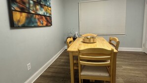 A dining area with a wooden table and chairs, a painting on the wall, and a window with blinds. - Cozy house in welcoming Cleveland with AC, WiFi (Cleveland)