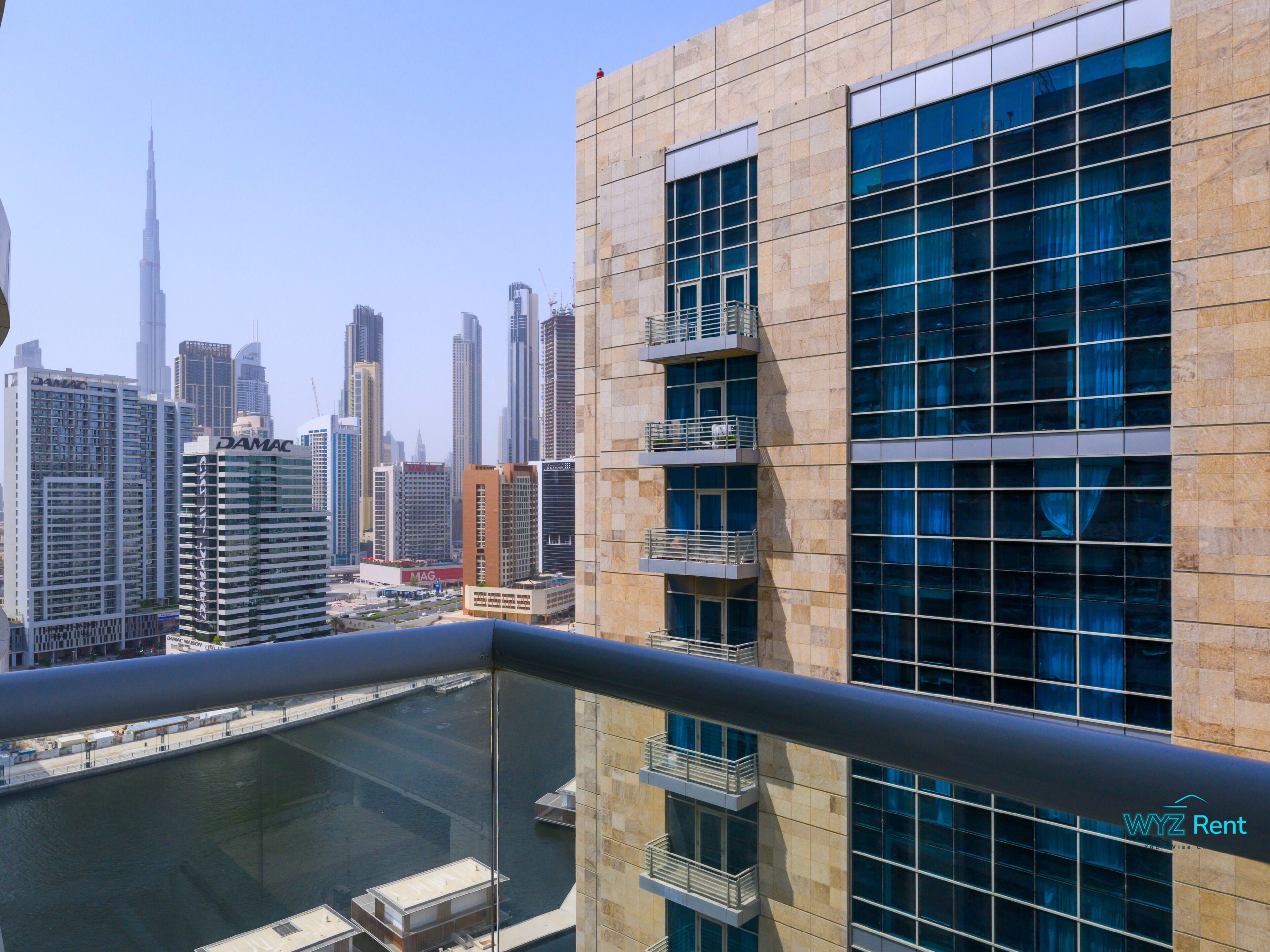 A modern building with multiple balconies and a view of the city skyline, including a prominent skyscraper.