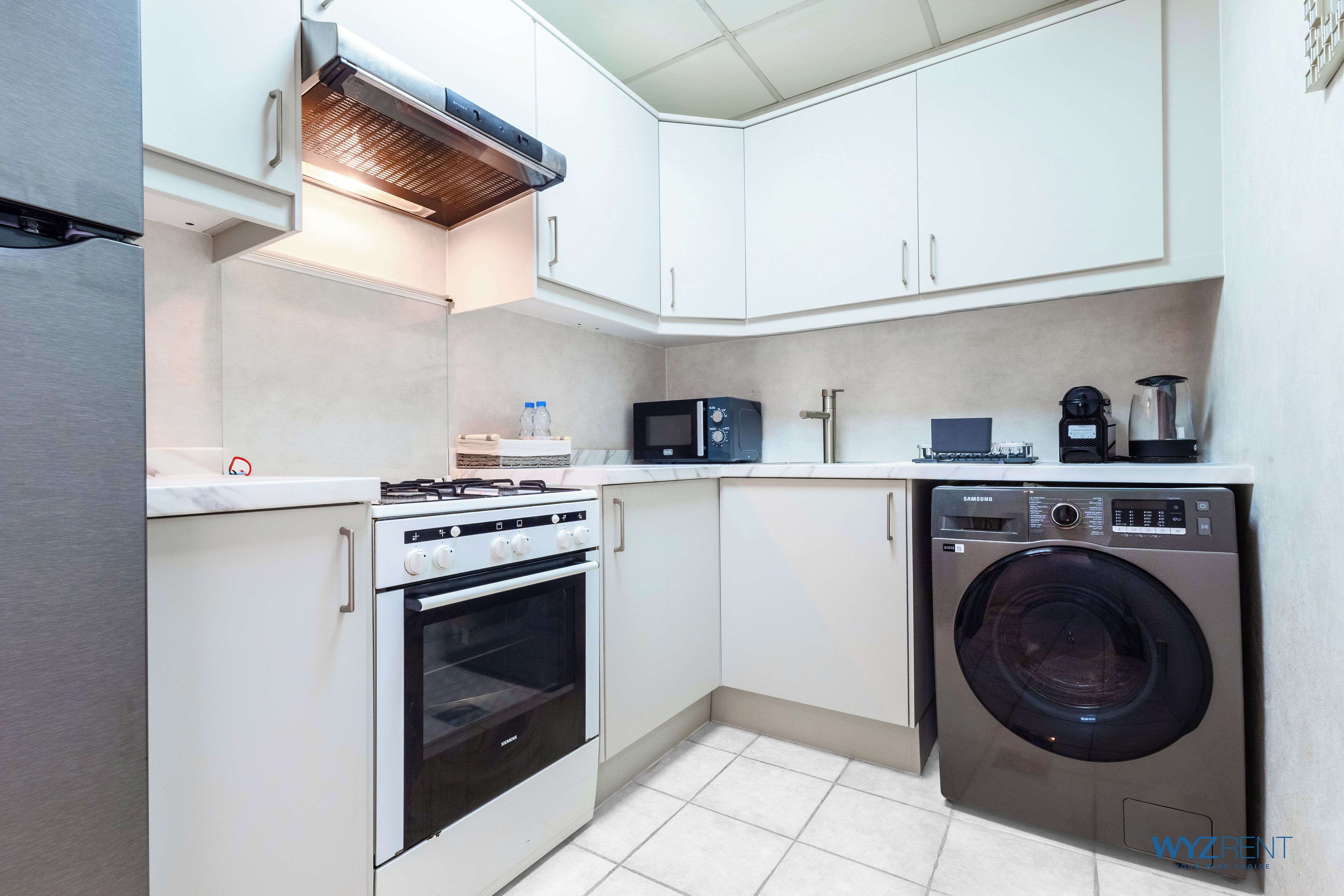 A compact kitchen with a built-in oven, microwave, and washing machine.