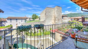 A balcony with a view of a stone building, a paved courtyard, and surrounding houses. - Henry-historic Center 300mt From Lake (San Felice del Benaco)