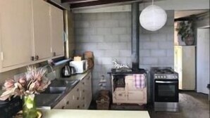 A kitchen with a stove, cabinets, and a hanging light fixture. - Moorestone- Back to Yesteryear (Guilderton)