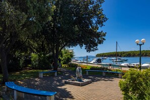 A park with benches, a sculpture, and a view of boats on the water.