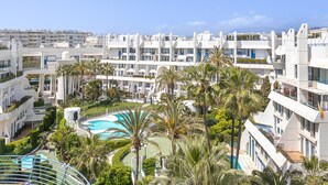 Un hôtel moderne à plusieurs étages, doté d’une piscine et bordé de palmiers.