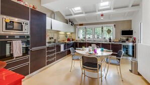 A modern kitchen with dark cabinetry, a central island, and a dining area with four chairs.