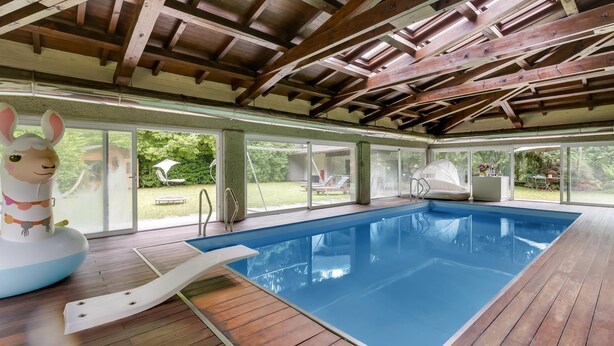 An indoor swimming pool with wooden beams, a slide, and a large inflatable rabbit decoration.
