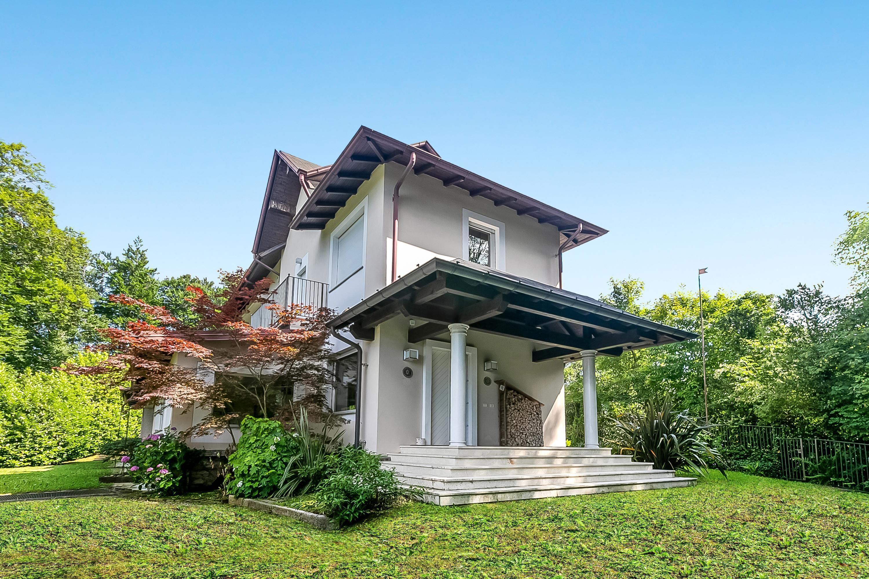 A two-story house with a covered porch and a small staircase leading to the entrance.