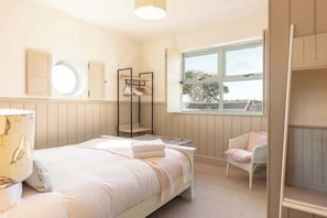 Un dormitorio con cama, una silla, un ventanal y un armario.