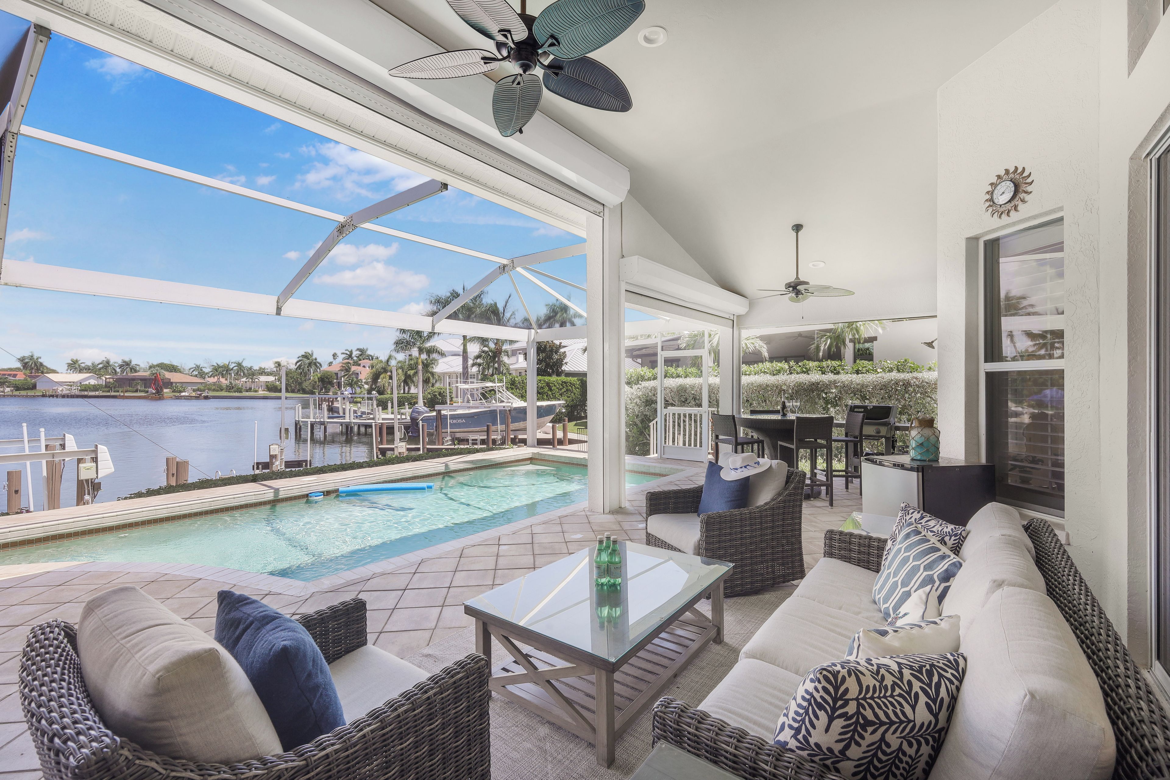 A spacious outdoor area with a pool, seating, and a view of the water.