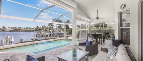 A spacious outdoor area with a pool, seating, and a view of the water.