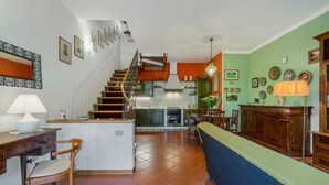A spacious living area with a kitchen, a dining table, and a staircase leading to an upper floor.