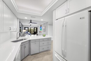 A modern kitchen with white cabinetry, a built-in sink, and a large refrigerator.