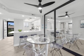 A modern kitchen with white cabinets, a glass island, and a ceiling fan.
