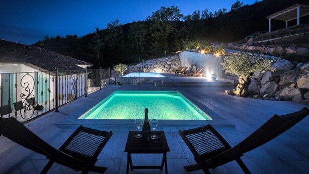 A rectangular swimming pool with a stone border, surrounded by lounge chairs and a table with a bottle and glasses. - Villa Lapis in Buzet (Buzet)