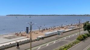 Un paseo marítimo junto a la playa, con calle y vista despejada al mar.