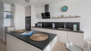 Una cocina moderna con una isla central, electrodomésticos integrados y un reloj de pared.