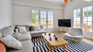 En stue med sofa, lænestole, sofabord og fjernsyn.