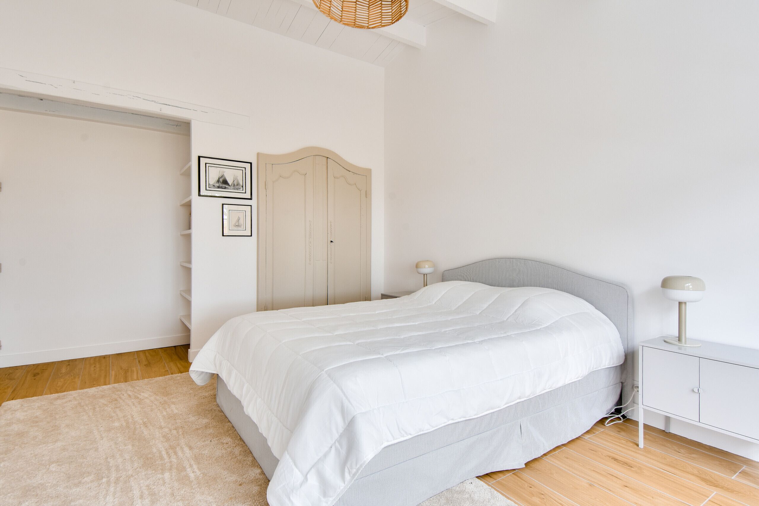 Une chambre à coucher avec un lit, une table de chevet, une lampe, une armoire et une porte.