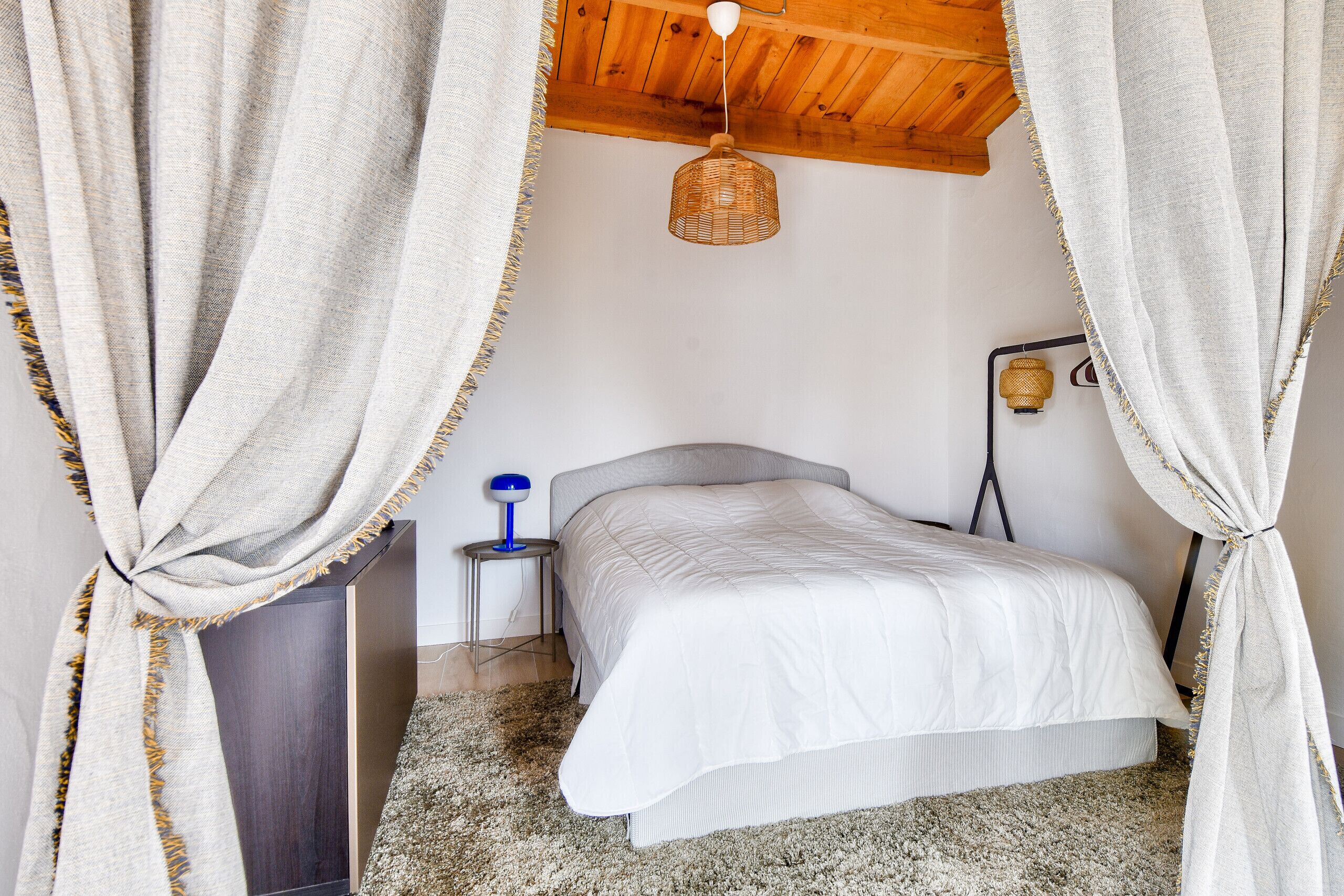 A bedroom with a bed, a nightstand, a lamp, and a ceiling light.