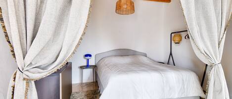 A bedroom with a bed, a nightstand, a lamp, and a ceiling light.