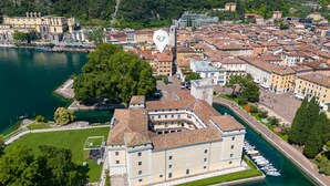 An aerial view of a historic building with a courtyard, surrounded by a body of water and adjacent urban buildings. - Life View Luxury Apartment (Riva del Garda)