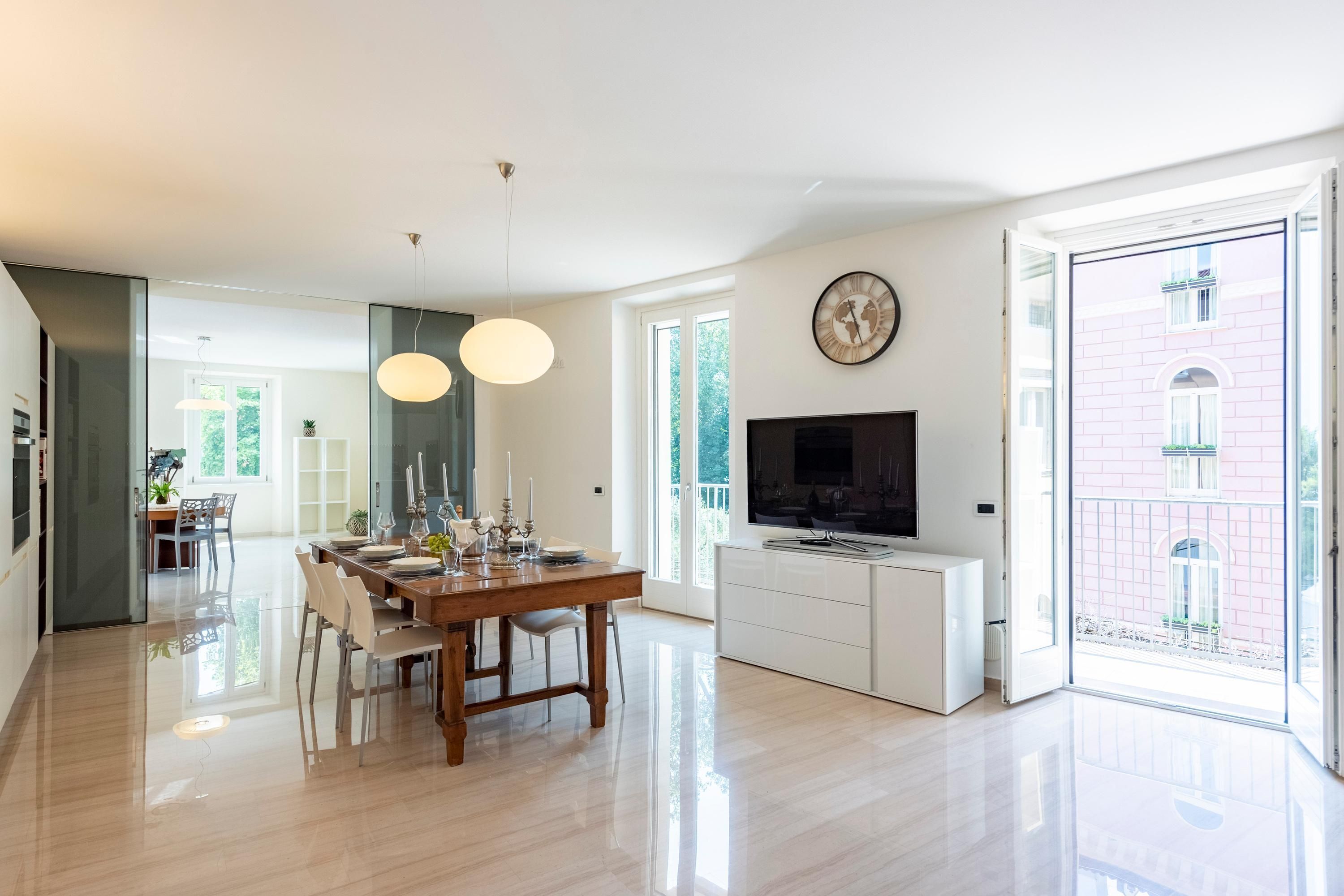 A modern kitchen with a dining area, large windows, and a TV.