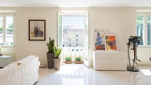 A bright living room with a sofa, potted plants, artwork, and a view through an open door. - Life View Luxury Apartment (Riva del Garda)