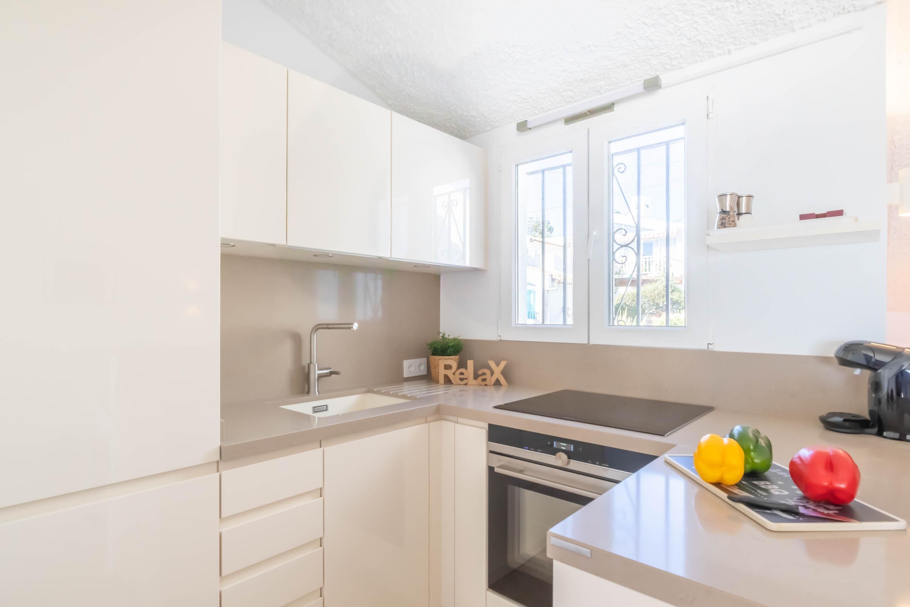 A modern kitchen with white cabinets, a built-in oven, and a sink.
