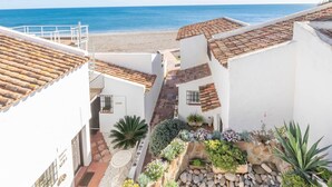 A coastal building with terracotta roofs, a stone pathway, and a garden with various plants. - Bahia Dorada Beach Casita G26 (Estepona)