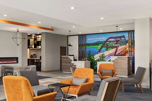 A hotel lobby with seating, a reception desk, a fireplace, and a mural of a bridge.