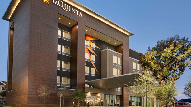 A modern hotel with a prominent 'La Quinta' sign, large windows, and a covered entrance. - La Quinta Inn & Suites By Wyndham Austin South (Austin)