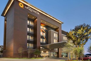 A modern hotel with a prominent 'La Quinta' sign, large windows, and a covered entrance.