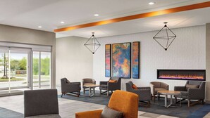 A modern lobby with seating areas, a fireplace, and large windows. - La Quinta Inn & Suites By Wyndham Austin South (Austin)