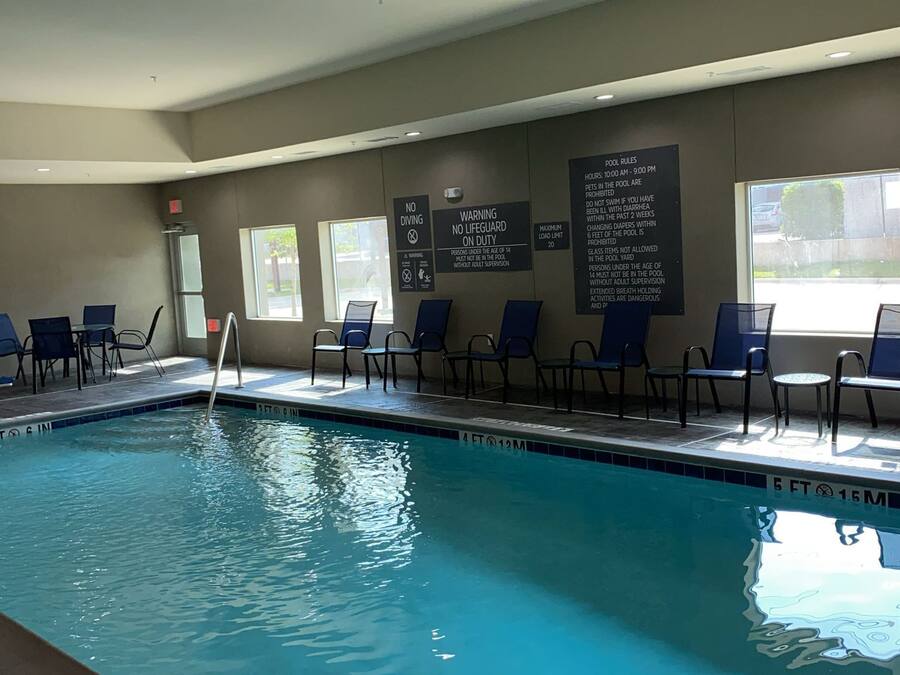 An indoor swimming pool with clear pool rules posted on the wall, including no diving and a maximum load limit.
