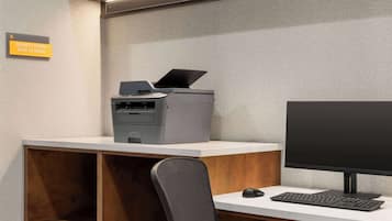 Escritorio de centro de negocios con una impresora, un monitor de computadora y un teclado.