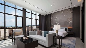 Une chambre d’hôtel moderne dotée d’une grande fenêtre, d’un canapé, d’une table basse, d’un lit et d’une table de chevet.
