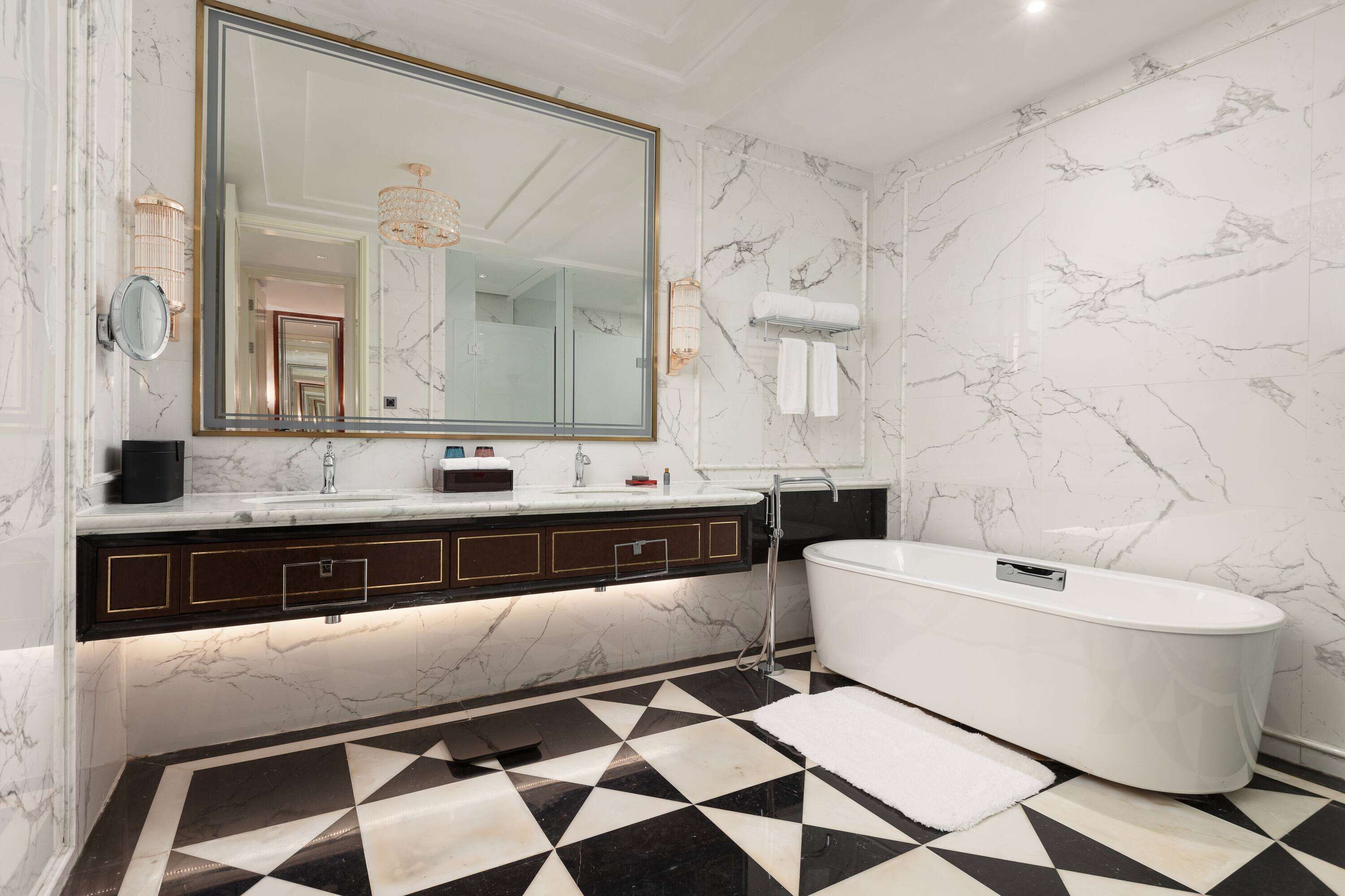 A bathroom with a large mirror, a freestanding bathtub, and a black and white checkered floor.